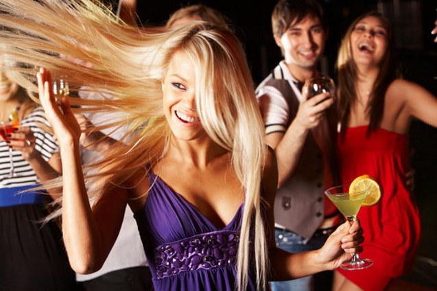 Portrait of cheerful girl with cocktail in hand having fun at discotheque